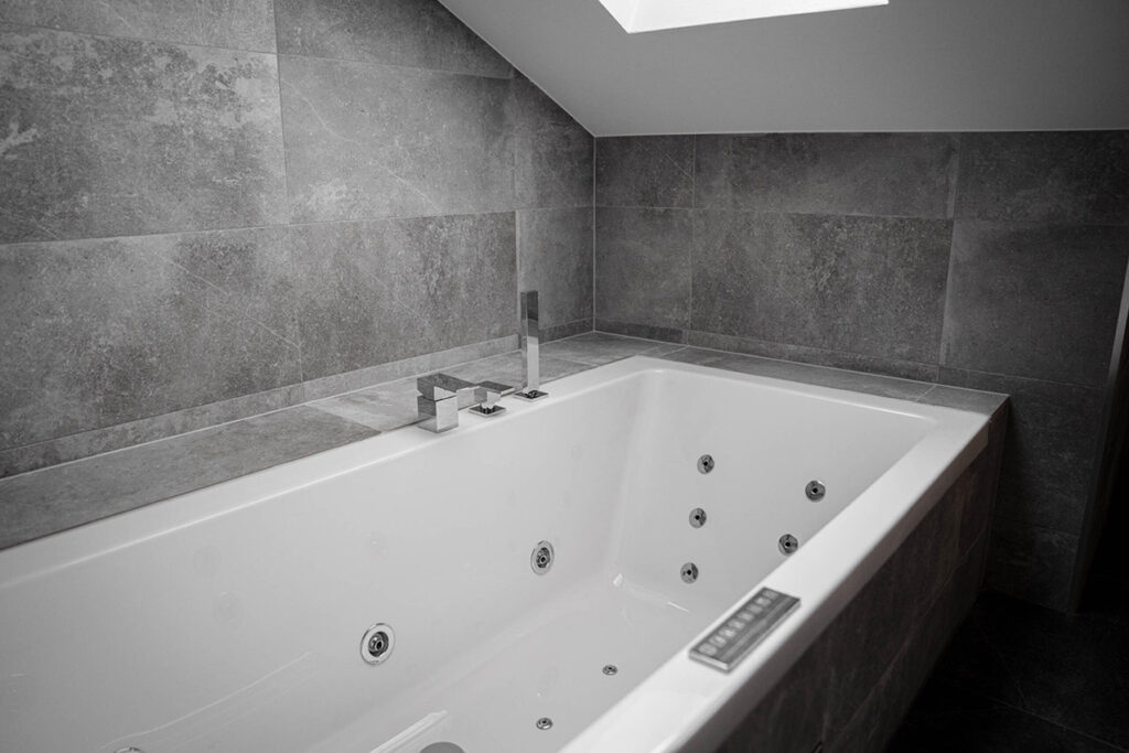 Vitt lyxigt badkar i ett badrum med ljusgrå granit klinkers i Stockholm