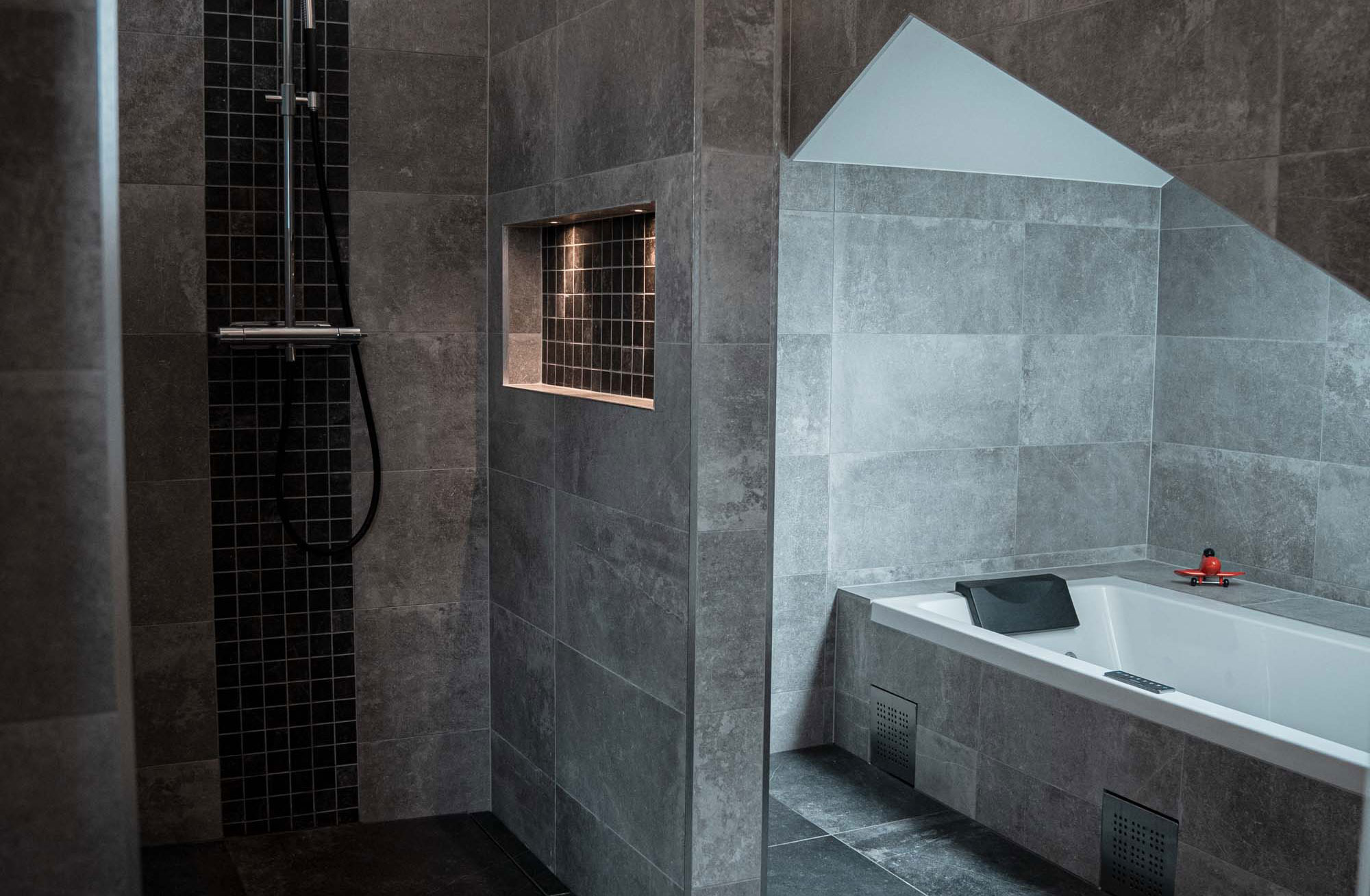 Badrum med ljusgrå granit med dusch och badkar och inbygd belysning i Sollentuna
