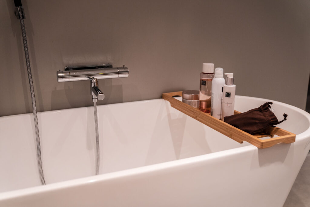 Vitt modernt badkar med en trähylla för badkaret med produkter från märket Rituals